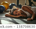 Young woman resting on a gym floor after an intense workout session 138708630