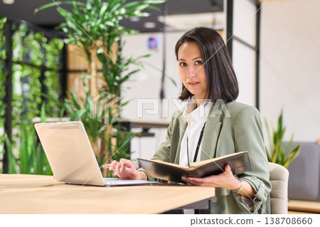 A female systems engineer taking notes while looking at her smartphone in the office of a foreign-owned IT company. A female systems engineer taking notes while looking at her smartphone in the office of a foreign-owned IT company. 138708660