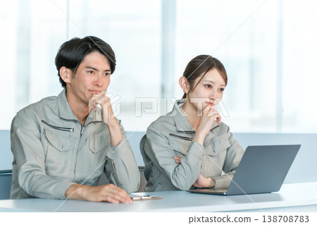 Serious-looking male and female staff members in work clothes lined up at desks where interviews, meetings, evaluations, and selections are conducted. 138708783