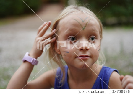 Child with Face Paint Touching Hair in Outdoor Setting Child with Face Paint Touching Hair in Outdoor Setting 138708936