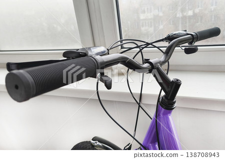 Close-up of a bicycle handlebar with brake lever and rubber grip, showing a modern purple bike detail, symbolizing mobility, fitness, and outdoor lifestyle 138708943