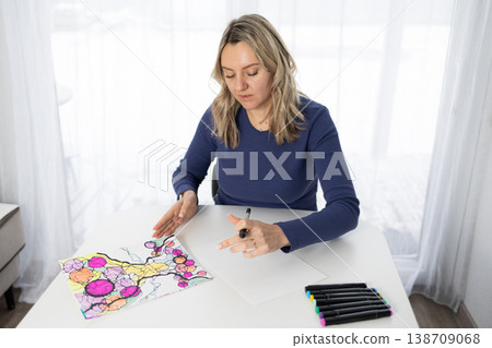 Woman Engages in Coloring Activity for Mental Health and Relaxation in a Bright Room Woman Engages in Coloring Activity for Mental Health and Relaxation in a Bright Room 138709068