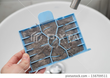 Dirty vacuum cleaner filter, clogged with lint, hair and dust. They want to wash him in the sink. 138709511