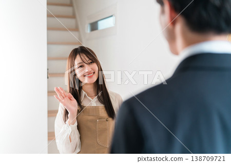 一位年輕的亞洲女性/妻子在早上上班時微笑著送行 一位年輕的亞洲女性/妻子在早上上班時微笑著送行 138709721