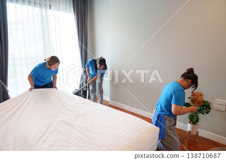 Team of cleaners tidying up a bedroom Team of cleaners tidying up a bedroom 138710687