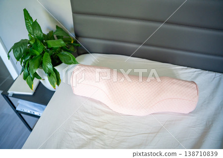 Ergonomic orthopedic pillow on bed in modern bedroom interior. Cervical support pillow for proper neck alignment, posture correction and comfortable healthy sleep at home 138710839