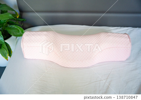 Ergonomic orthopedic pillow on bed in modern bedroom interior. Cervical support pillow for proper neck alignment, posture correction and comfortable healthy sleep at home Ergonomic orthopedic pillow on bed in modern bedroom interior. Cervical support pillow for proper neck alignment, posture correction and comfortable healthy sleep at home 138710847