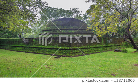 Ancient Royal Palace Ruins in Polonnaruwa, Sri Lanka. Ancient brick structure with moss-covered walls nestled in a lush green landscape under a cloudy sky Ancient Royal Palace Ruins in Polonnaruwa, Sri Lanka. Ancient brick structure with moss-covered walls nestled in a lush green landscape under a cloudy sky 138711006