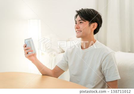 A young Asian man drinking canned beer and canned chu-hi (a type of Japanese alcoholic beverage) at night in his bedroom at home. A young Asian man drinking canned beer and canned chu-hi (a type of Japanese alcoholic beverage) at night in his bedroom at home. 138711012