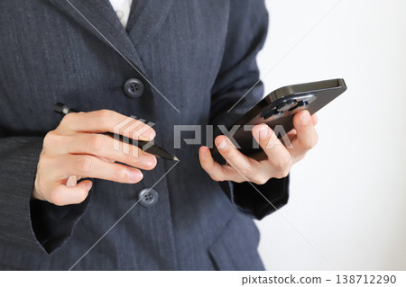A woman in a suit using a smartphone A woman in a suit using a smartphone 138712290