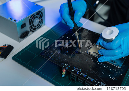 Computer Hardware Technician Repairing Motherboard with Soldering Iron in Electronics Lab. 138712703