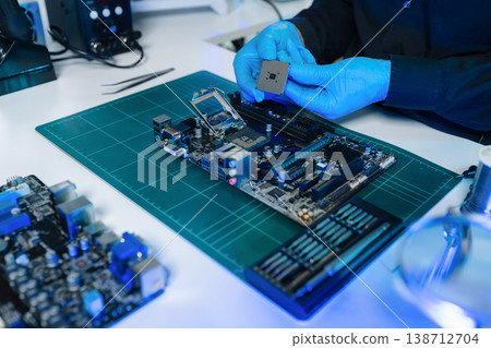 Computer Hardware Technician Repairing Motherboard with Soldering Iron in Electronics Lab. Computer Hardware Technician Repairing Motherboard with Soldering Iron in Electronics Lab. 138712704