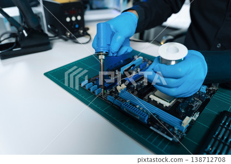 Computer Hardware Technician Repairing Motherboard with Soldering Iron in Electronics Lab. 138712708