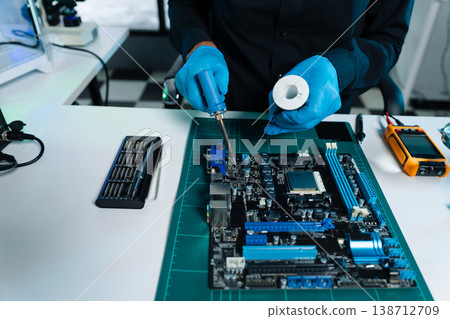 Computer Hardware Technician Repairing Motherboard with Soldering Iron in Electronics Lab. 138712709