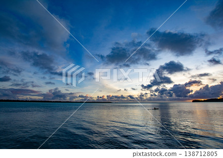 The sea at sunset and a person paddling a kayak. The sea at sunset and a person paddling a kayak. 138712805
