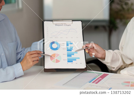 Team members analyzing report charts in a meeting Team members analyzing report charts in a meeting 138713202