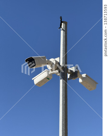 Surveillance cameras mounted on a metal pole under clear blue sky strong lighting background Surveillance cameras mounted on a metal pole under clear blue sky strong lighting background 138713593