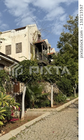 Mediterranean residential street with historic building surrounded by lush greenery under blue sky Mediterranean residential street with historic building surrounded by lush greenery under blue sky 138713597