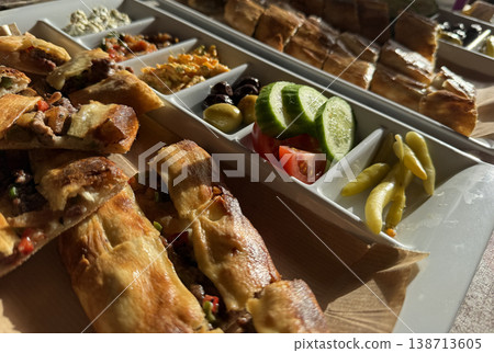 Turkish pide and assorted appetizers served on a platter under warm sunlight. Turkish pide and assorted appetizers served on a platter under warm sunlight. 138713605