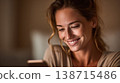 Woman smiles while looking at phone 138715486