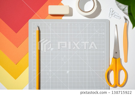 Top view creative workspace with cutting mat, scissors, glue, pencil and orange paper on white desk. Copyspace Top view creative workspace with cutting mat, scissors, glue, pencil and orange paper on white desk. Copyspace 138715922