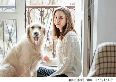 Woman bonding with dog sitting by balcony window 138716182