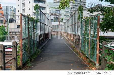 在日暮里和鶯谷之間的鐵路線上有一座高架橋，透過鏽跡斑斑的圍欄，可以看到城市天際線和駛過的火車。 138716598