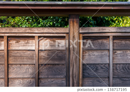 Close-up of a wooden fence and wooden wall in a traditional Japanese building. The beautiful wood grain texture of the fence serves as a security enclosure for an old house. Close-up of a wooden fence and wooden wall in a traditional Japanese building. The beautiful wood grain texture of the fence serves as a security enclosure for an old house. 138717195