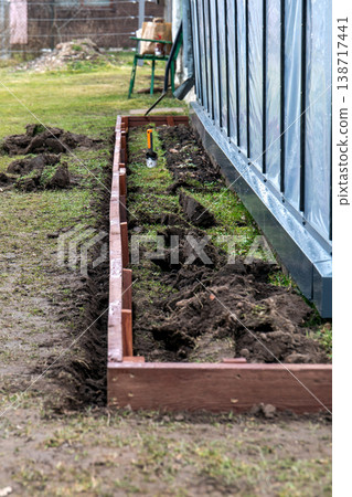 Preparing Long Raised Garden Bed Frame With Soil Digging Along Greenhouse Wall Preparing Long Raised Garden Bed Frame With Soil Digging Along Greenhouse Wall 138717441