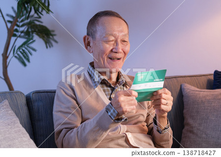 Senior man smiles as he looks at his bankbook. Senior man smiles as he looks at his bankbook. 138718427