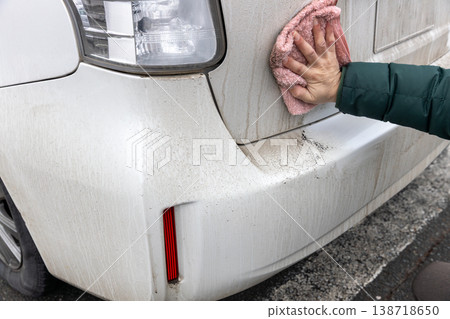 I'm wiping the dirty car body with a damp cloth. 138718650