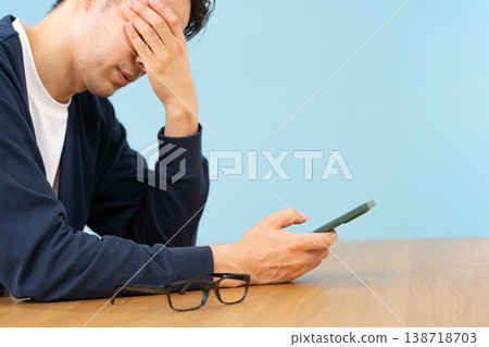 A man looking at his smartphone, seemingly troubled; his hands are close up, sideways. A man looking at his smartphone, seemingly troubled; his hands are close up, sideways. 138718703