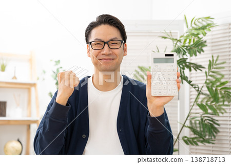 A man holding a calculator makes a triumphant gesture. A man holding a calculator makes a triumphant gesture. 138718713