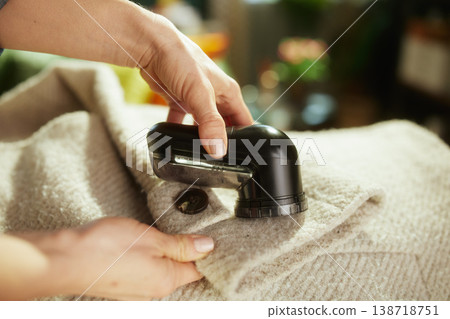 Hands Using Fabric Shaver to Remove Pilling from Wool Sweater 138718751
