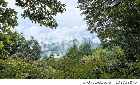 A misty mountain landscape seen through the frame of trees. A misty mountain landscape seen through the frame of trees. 138718870