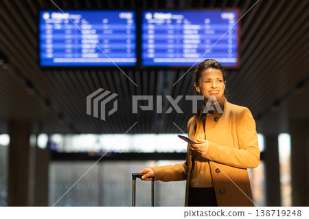 Confident Business Traveler Smiling with Phone and Suitcase Confident Business Traveler Smiling with Phone and Suitcase 138719248