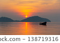 Serene sunrise in Phuket over calm sea with silhouette of boat and distant islands, creating tranquil atmosphere 138719316