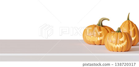 Three carved pumpkins are placed on a tabletop with empty space around them. The pumpkins show various facial designs in a Halloween theme. The background is clear and bright 138720317
