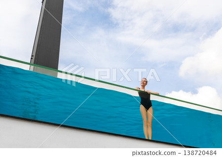 Young adult caucasian sporty slim smiling relaxing woman enjoy stand in pool with clear blue water and trasparent wall edge against sky at luxury spa resort. Healthy lifestyle and wellness concept Young adult caucasian sporty slim smiling relaxing woman enjoy stand in pool with clear blue water and trasparent wall edge against sky at luxury spa resort. Healthy lifestyle and wellness concept 138720484