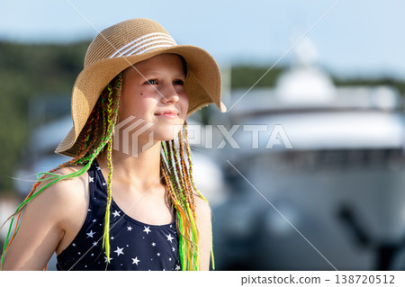 Girl wearing straw hat swimsuit stand sea luxury yachts marina during sunny summer vacation. Travel lifestyle, childhood freedom and seaside tourism atmosphere with blue water and resort background 138720512