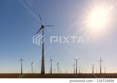 Wind turbines park agricultural field Germany clear blue sky produce renewable electricity. Wind farm landscape sustainability climate energy transition independence during European energy crisis Wind turbines park agricultural field Germany clear blue sky produce renewable electricity. Wind farm landscape sustainability climate energy transition independence during European energy crisis 138720686