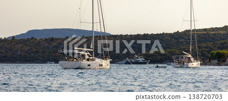 Sailboats anchored calm sea bay mediterranean coast green hills clear sky during warm summer evening. Scenic marine landscape yachts travel leisure atmosphere tranquil seaside tourism destination 138720703