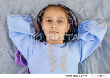 Close-up portrait of a young girl resting on a picnic blanket outdoors. Close-up portrait of a young girl resting on a picnic blanket outdoors. 138720986