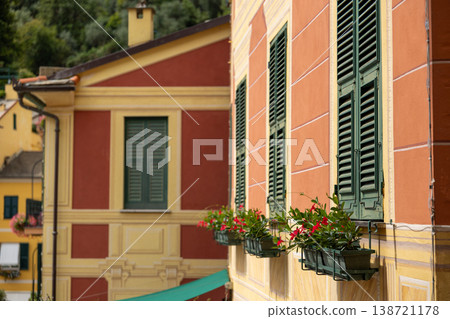 Warm pastel building facade with traditional green shutters and blooming flower boxes. Warm pastel building facade with traditional green shutters and blooming flower boxes. 138721178