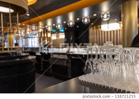 Elegant bar interior with neatly arranged wine glasses on a counter and warm atmospheric lighting. Elegant bar interior with neatly arranged wine glasses on a counter and warm atmospheric lighting. 138721255