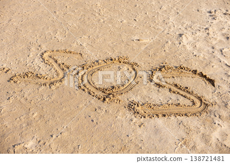 SOS Message Written On Sandy Beach Surface Emergency Help Concept Background  138721481