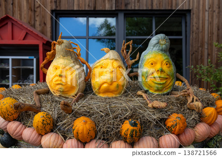 Creative carved pumpkins with human faces on hay bale decoration, autumn harvest art installation and halloween seasonal farm festival concept Creative carved pumpkins with human faces on hay bale decoration, autumn harvest art installation and halloween seasonal farm festival concept 138721566