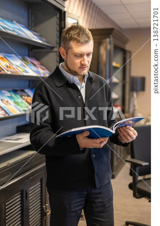 Professional Man Reading Brochure In Office Library Area With Corporate Interior Design Professional Man Reading Brochure In Office Library Area With Corporate Interior Design 138721701