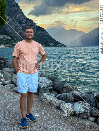 Man Traveler Standing On Rocky Shore Of Mountain Lake During Sunset Scenic Nature Landscape 138721822