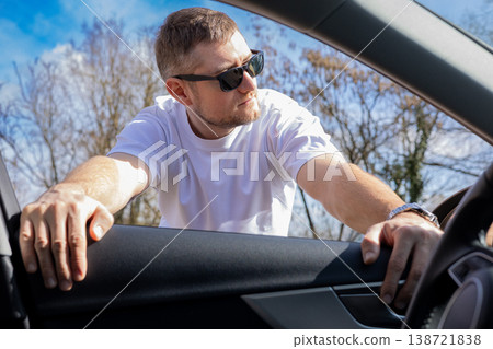 Confident man leaning into car window checking interior in sunny day casual lifestyle transport concept Confident man leaning into car window checking interior in sunny day casual lifestyle transport concept 138721838
